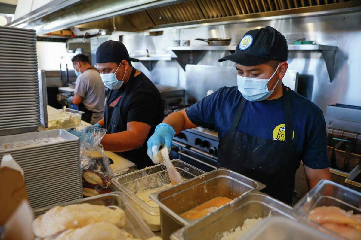 Prep cook Byron Chavix (right) wears a mask as he prepares for dinner service at Wursthall on Friday, July 16, 2021 in San Mateo, California.