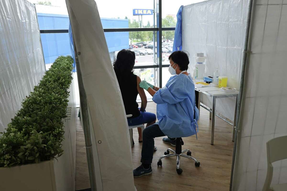 A doctor inoculates a woman against COVID-19 at a vaccination center inside a store of home furnishings retailer IKEA on August 05, 2021 in Berlin, Germany.