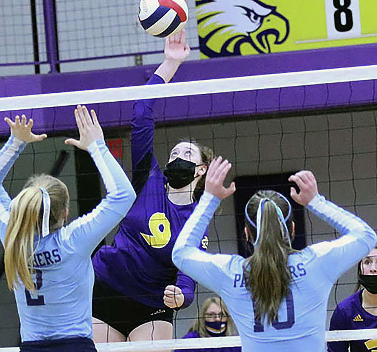 CM’s Lauren Dunlap (9) attacks before Jersey’s Sally Hudson and Caroline Gibson (10) can put up a block in a March 18 volleyball match in Bethalto. Volleyball teams, as well as athletes playing other indoor fall sports, will be required to wear masks temporarily, according to the IHSA.