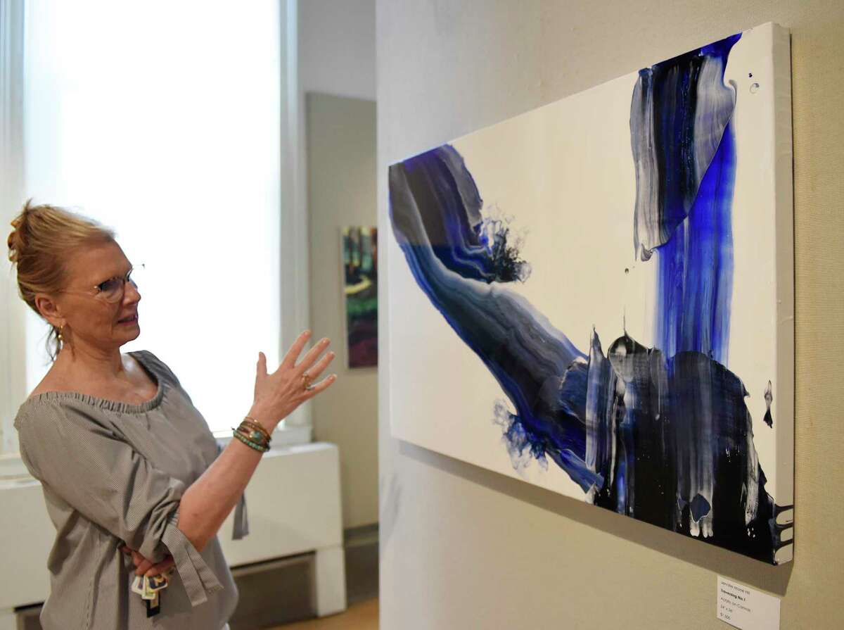 Greenwich Art Society Co-Director Mary Newcomb looks at Jennifer Mone Hill's painting "Traversing No. 1" at the Greenwich Art Society's 104th Annual Juried Exhibition at the Bendheim Gallery in Greenwich, Conn. Tuesday, July 27, 2021. The work, in a variety of mediums, was judged by Allison Rudnick, Associate Curator in the department of Drawings and Prints at the Metropolitan Museum of Art.