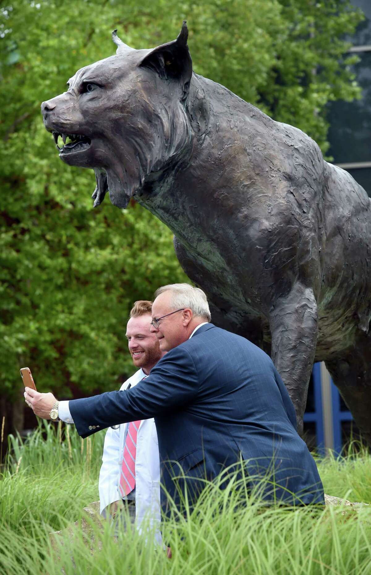 John Baekey, left, takes a photograph with his father, Greg Baekey, of Fairfield under the bobcat statue in front of Quinnipiac University's People's United Center in Hamden after the class of 2025 White Coat Ceremony Aug. 5, 2021.