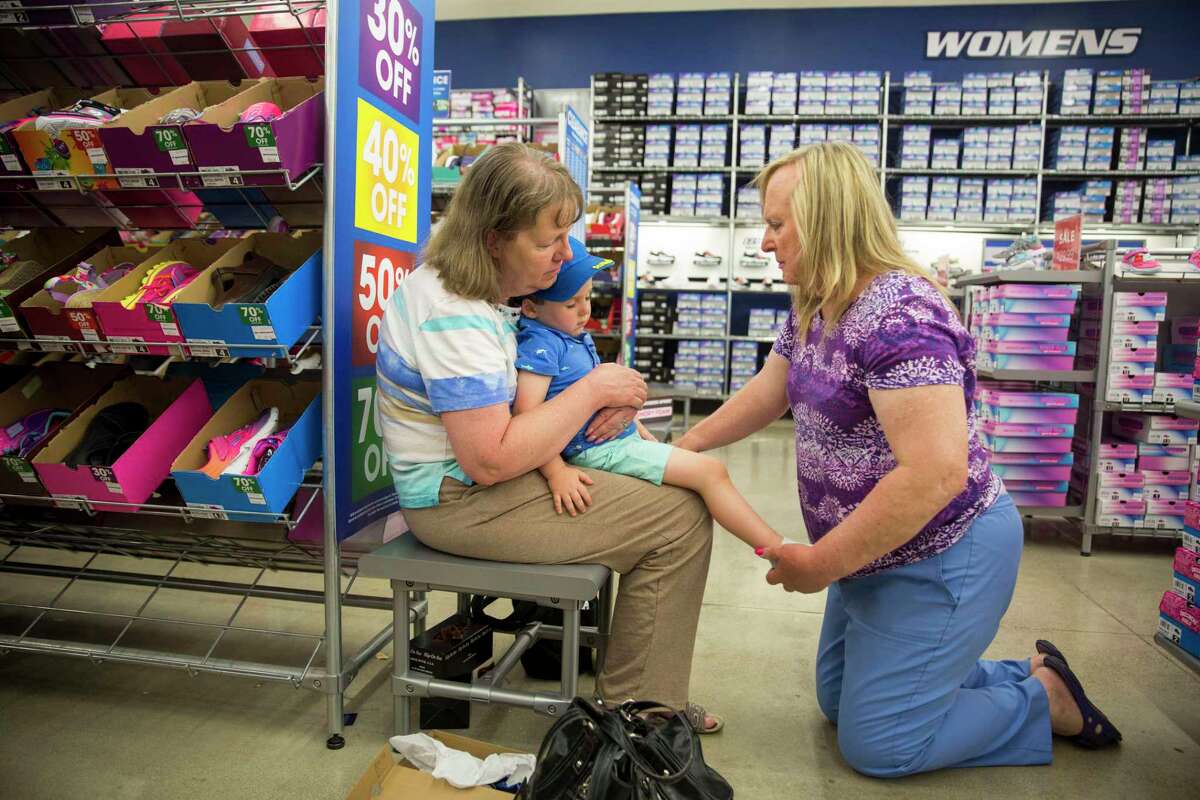 Kerry Farris holds her grandson Austin Farris as Lauryn Farris puts shoes on Austin at a Sketchers Outlet store in .