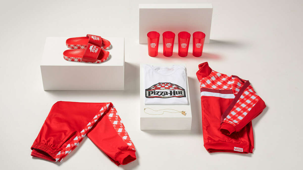 Pizza Hut is now selling track suits and slides with designs inspired by the iconic Pizza Hut red roof, checkered tablecloths and Tiffany-style lamps. 