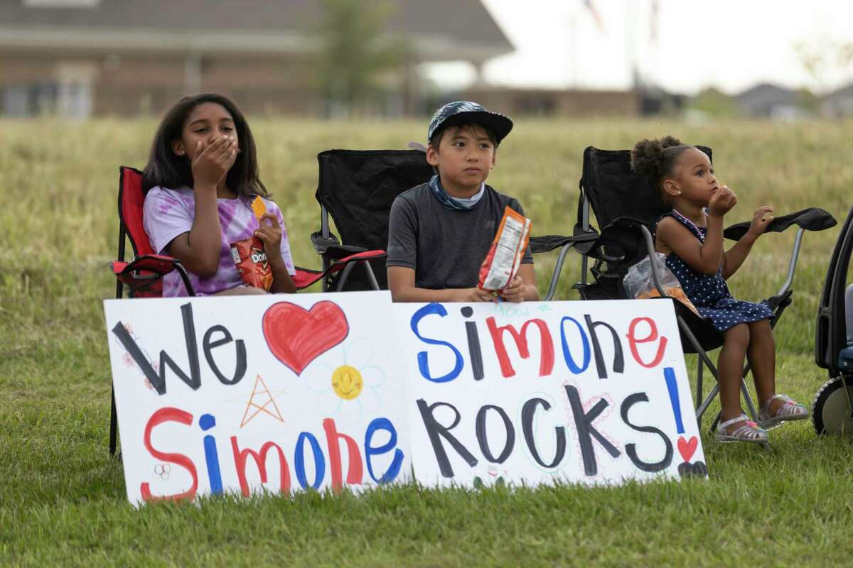 Supporters sit on the curb as they await Simone Biles arrival during a welcome home parade for Biles in her neighborhood of Benders Landing, Thursday, Aug. 5, 2021, in Spring. Biles is returning to Houston after winning two Olympic medals at the 2020 Tokyo Olympics.