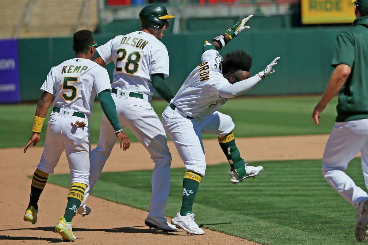 Oakland Athletics Matt Olson (28) celebrates his walk-off double with the A’s Josh Harrison (1) and Tony Kemp (5) as they win the MLB game against the San Diego Padres in the tenth inning at RingCentral Coliseum on Wednesday, Aug. 4, 2021, in Oakland, Calif. The Athletics won 5-4.