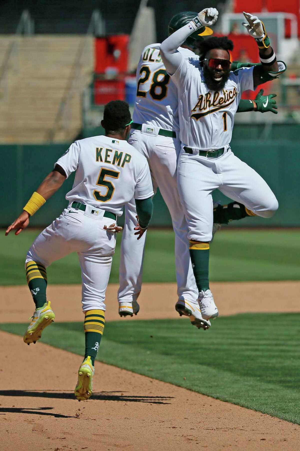 Oakland Athletics Matt Olson (28) celebrates his walk-off hit with the A’s Josh Harrison (1) and Tony Kemp (5) to win the MLB game against the San Diego Padres in the tenth inning at RingCentral Coliseum on Wednesday, Aug. 4, 2021, in Oakland, Calif. The Athletics won 5-4.