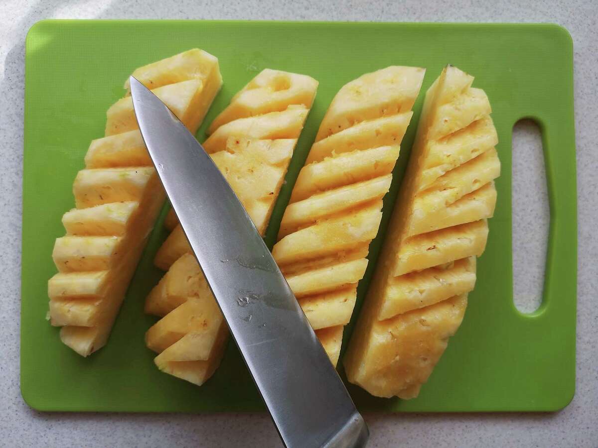 Cutting a pineapple is easy if you remove the peels and slice out the eyes in a spiral pattern.