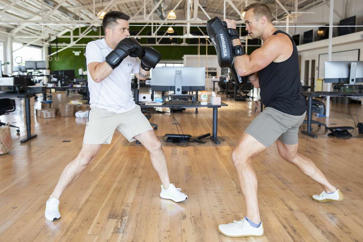 Phil McDougall (right), wellness director at the company Fast, spars with Domm Holland in a training session at the Fast office in San Francisco.