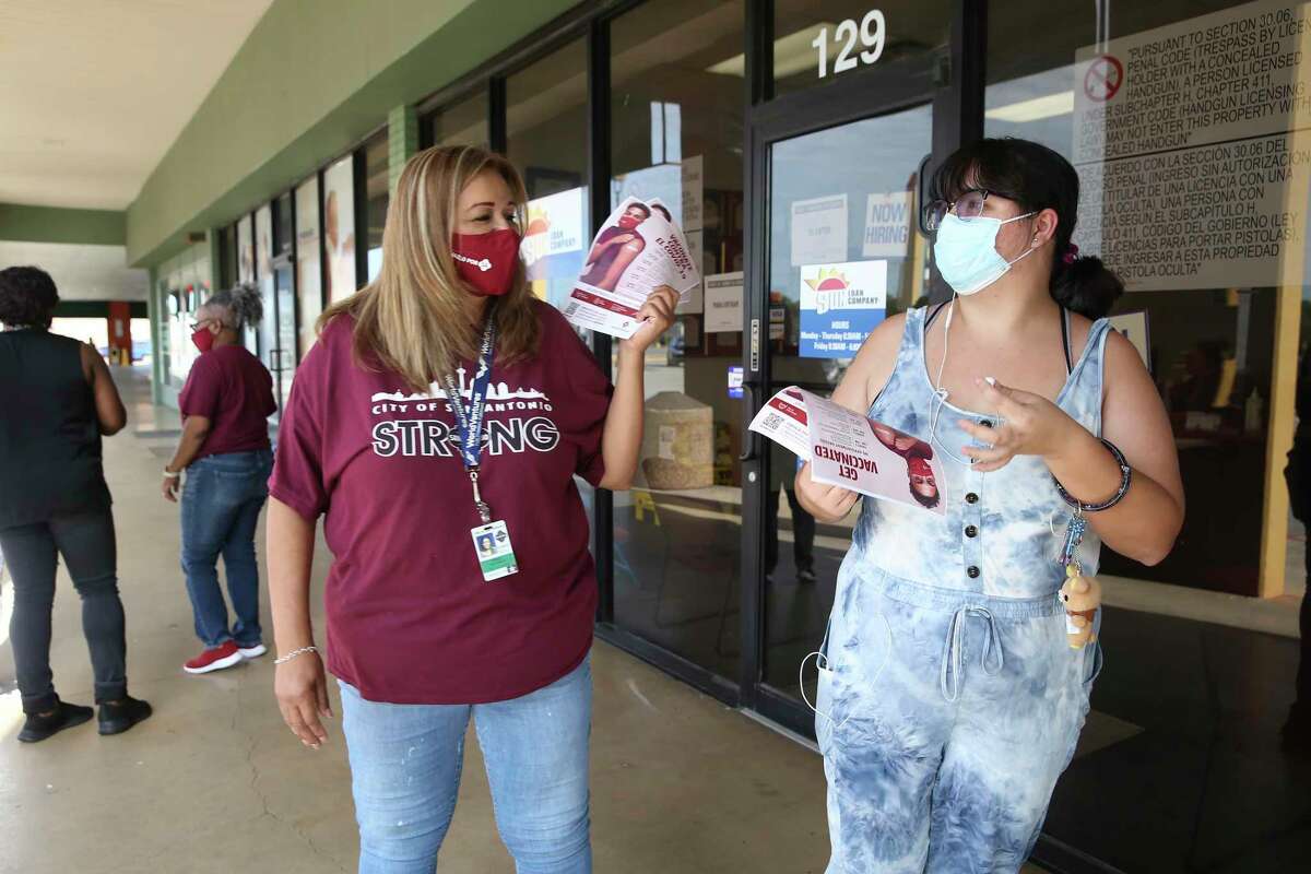 Christa Chavez, 21, right, gets information on upcoming free COVID-19 events from San Antonio Metropolitan Health District worker Mikela Villarreal at Las Palmas Shopping Center on the city’s West Side on Friday.