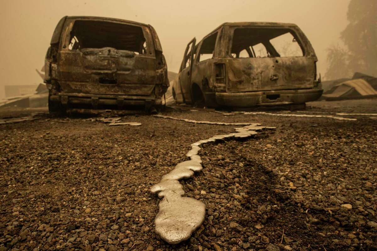 Solidified molten metal is seen behind two vehicles burned by the Dixie Fire in Greenville (Plumas County).