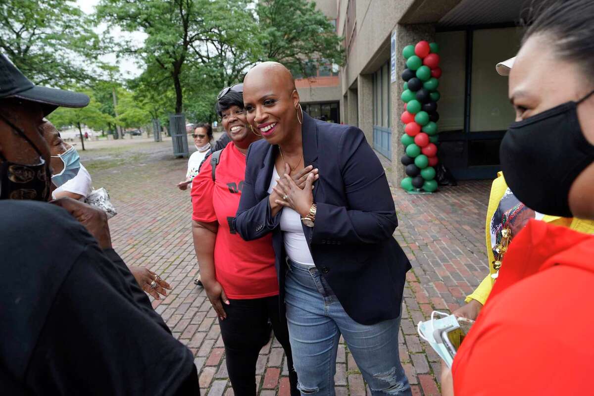 FILE - In this July 18, 2021 file photo, U.S. Rep. Ayanna Pressley, D-Mass., center, greets people before the start of the Roxbury Unity Parade, in Boston's Roxbury neighborhood. As workers return to the office, friends reunite and more church services shift from Zoom to in person, this exact question is befuddling growing numbers of people: to shake or not to shake.