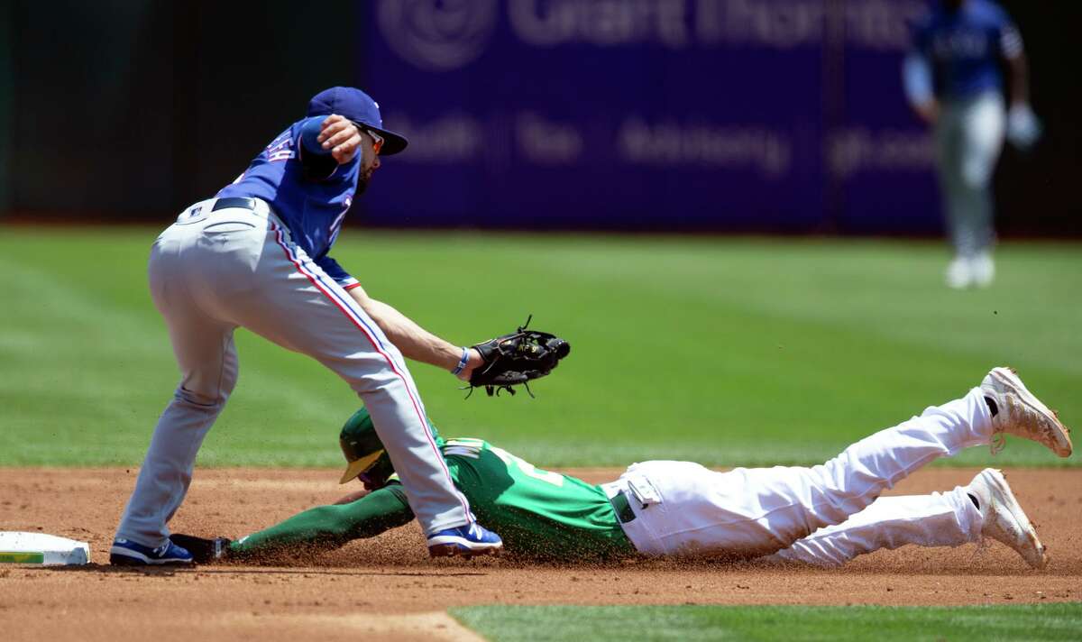 The A’s Starling Marte slides into second with a stolen base under the tag of Rangers shortstop Isiah Kiner-Falefa in the first.