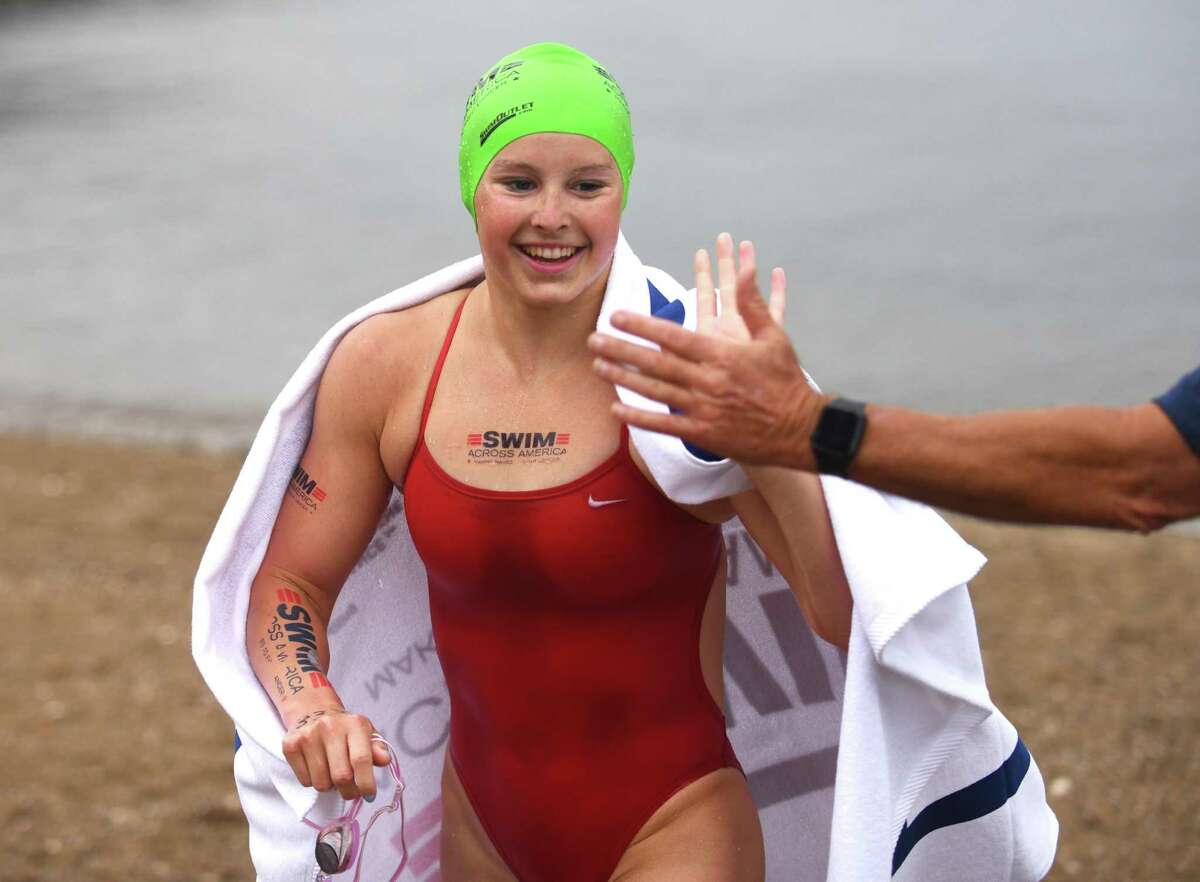 Greenwich’s Meghan Lynch gets a high-five after swimming 3 miles at the Swim Across America Fairfield County event at Cummings Point in Stamford on Sunday.