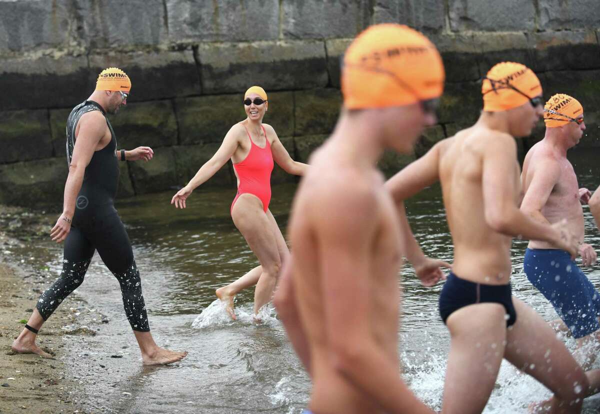 Swimmers take to the water and cheer on one another during the Swim Across America Fairfield County event at Cummings Point in Stamford on Sunday. More than $360,000 was raised at the event for the Alliance for Cancer Gene Therapy, a local nonprofit that funds research in cell and gene therapies to treat cancer. Swimmers swam routes ranging from half a mile to three miles as hundreds cheered them on from the shore.