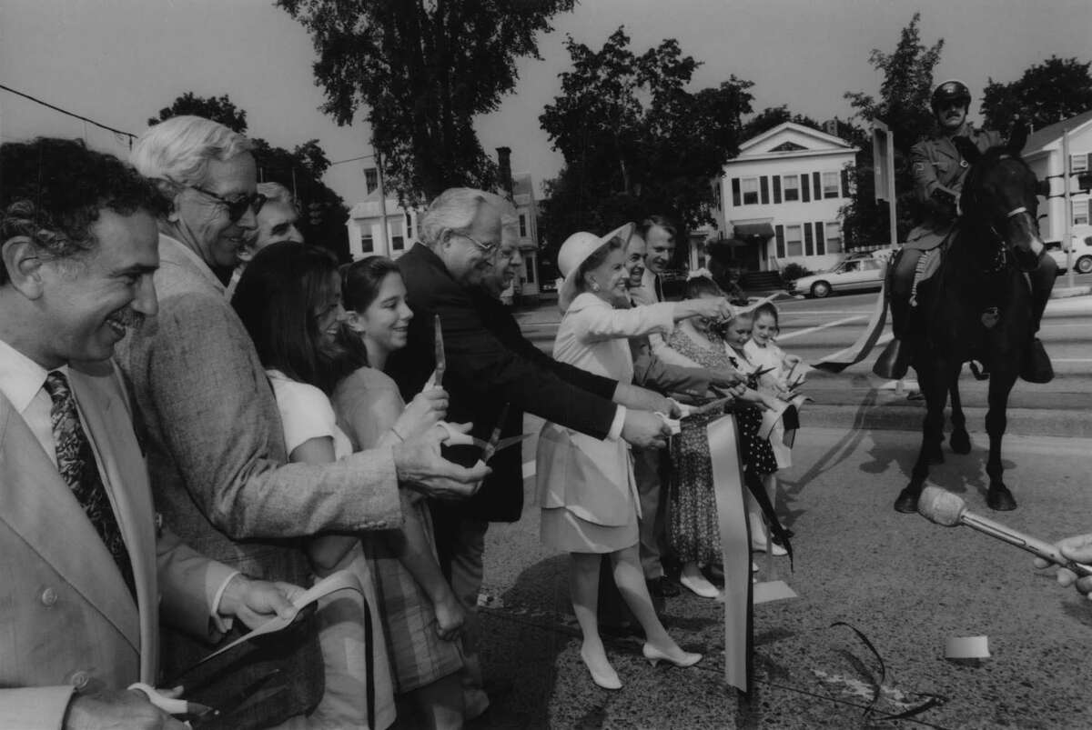 Route 50 at Broadway in Saratoga Springs, New York - Mary Lou Whitney, in center along with family members and other dignitaries, cuts a ribbon strung across the Route 50 arterial near Broadway. That section of the arterial from Broadway to the Northway was officially renamed the C.V. Whitney Memorial Highway after Mary Lou's husband, Sonny. At right is Sergeant Richard Pelzer of the State Park Police. August 9, 1994 (Paul D. Kniskern Sr./Times Union Archive)