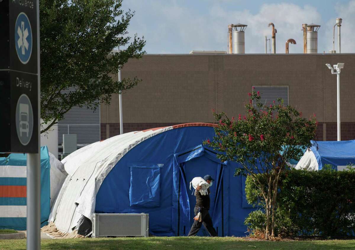A construction crew works to setup tents in case of overflow COVID-19 and ICU patients outside Lyndon B. Johnson Hospital on Monday, Aug. 9, 2021, in Houston.