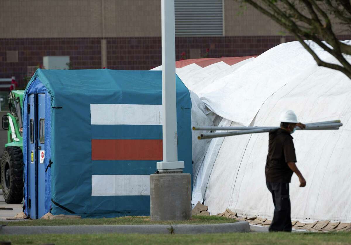 A construction crew works to setup tents to make room for a possible overflow of patients outside Lyndon B. Johnson Hospital on Monday, Aug. 9, 2021, in Houston.