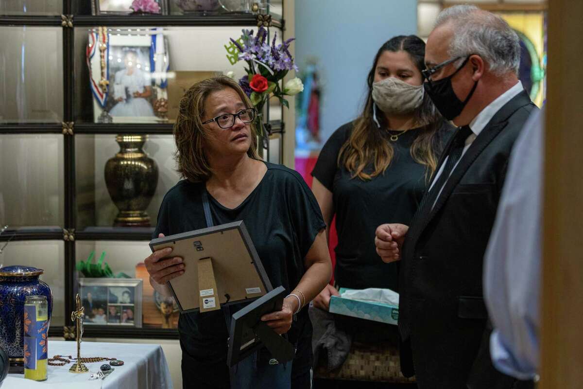 Cassandra Quinto-Collins (left), daughter Bella Collins and Robert Collins prepare to place Angelo Quinto’s photographs in his niche at Holy Cross Cemetery and Funeral Center in Antioch on June 23.