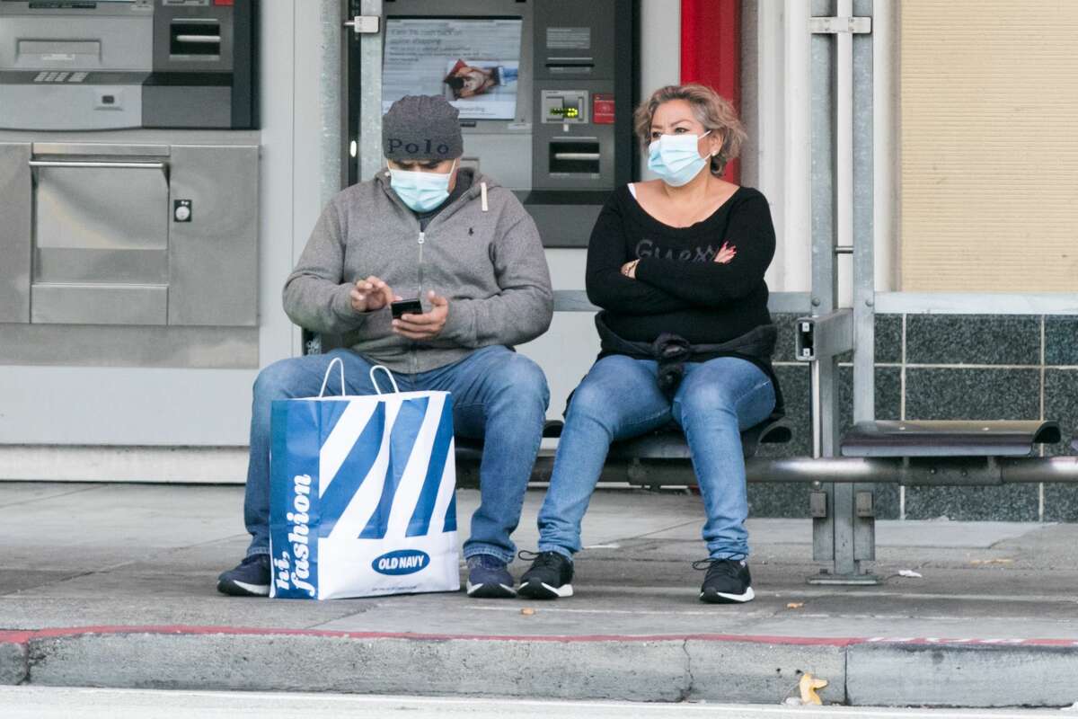 Passengers waiting for a MUNI bus wear face masks in San Francisco on Aug. 5, 2021.