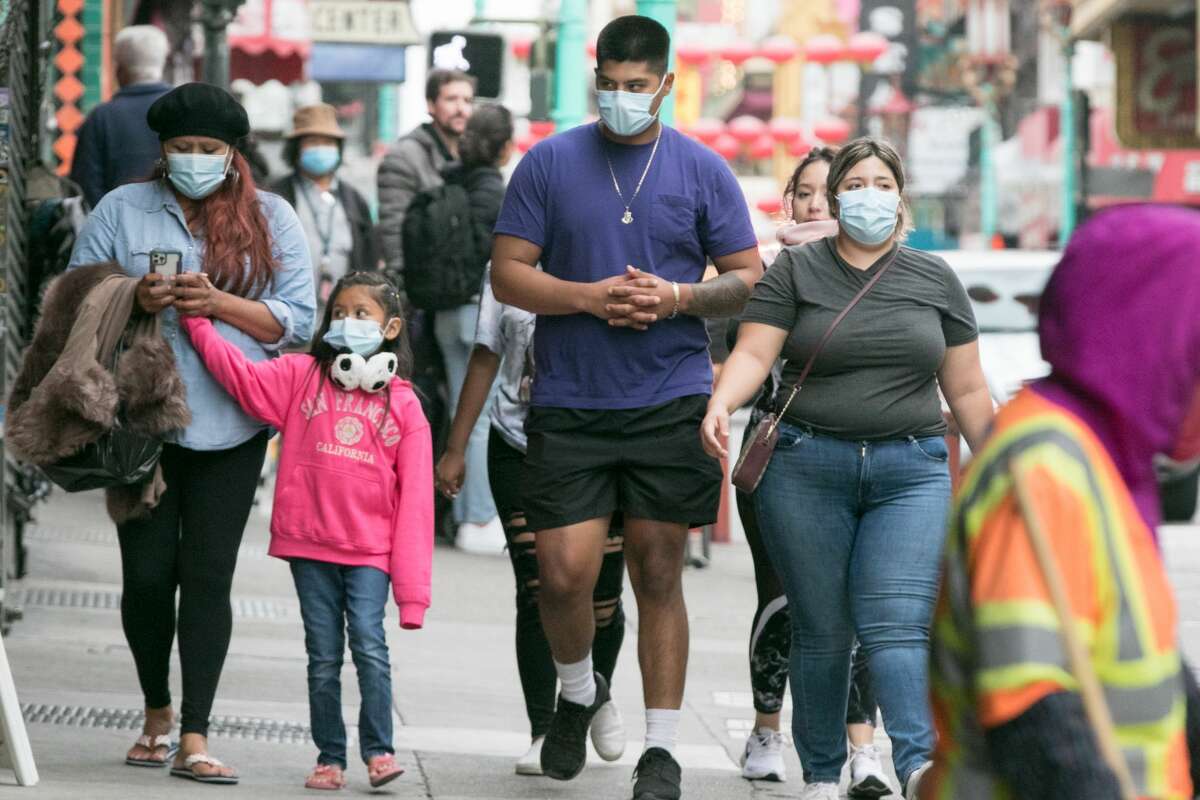 A family walking down Grant Avenue wear face masks in San Francisco on Aug. 5, 2021.
