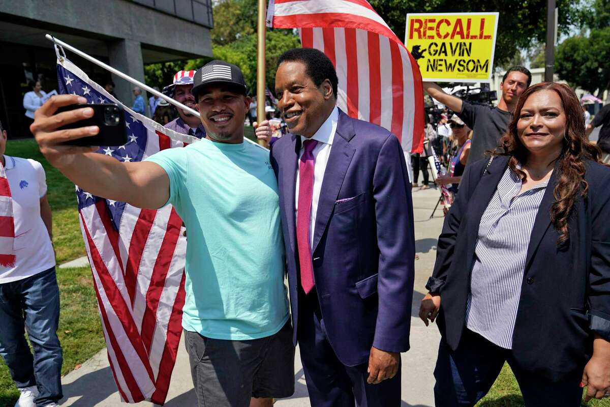 Radio talk show host Larry Elder, center, poses for selfies with supporters during a campaign stop Tuesday, July 13, 2021, in Norwalk, Calif.