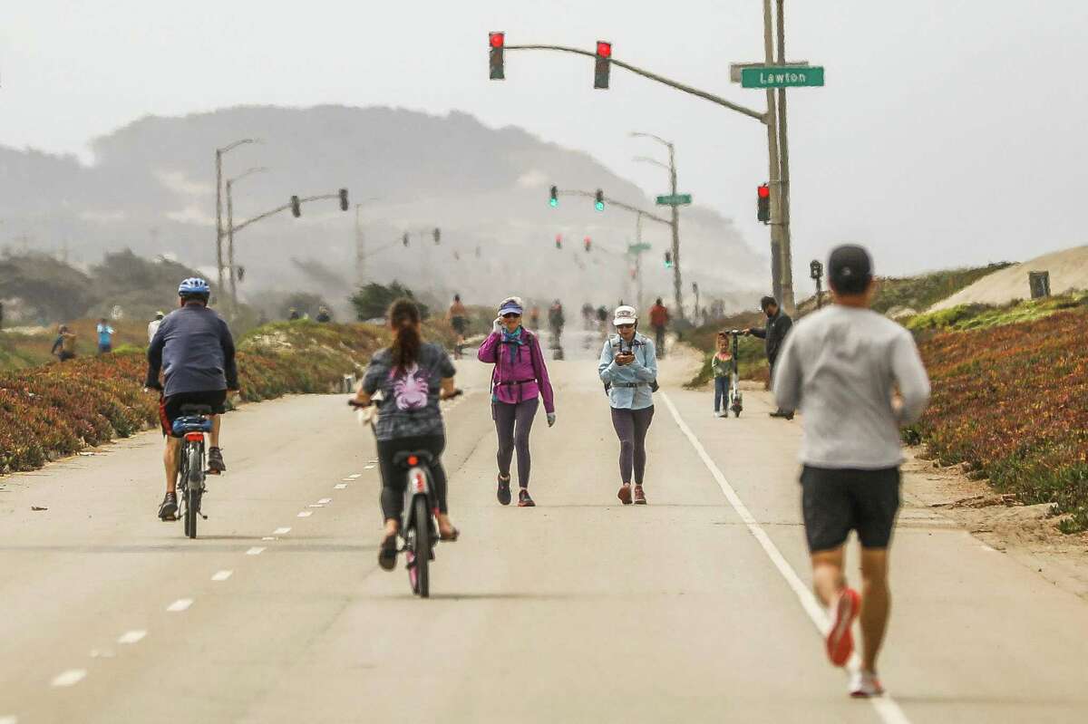 People walk and bike along Great Highway on Tuesday, Aug. 10, 2021 in San Francisco, California.