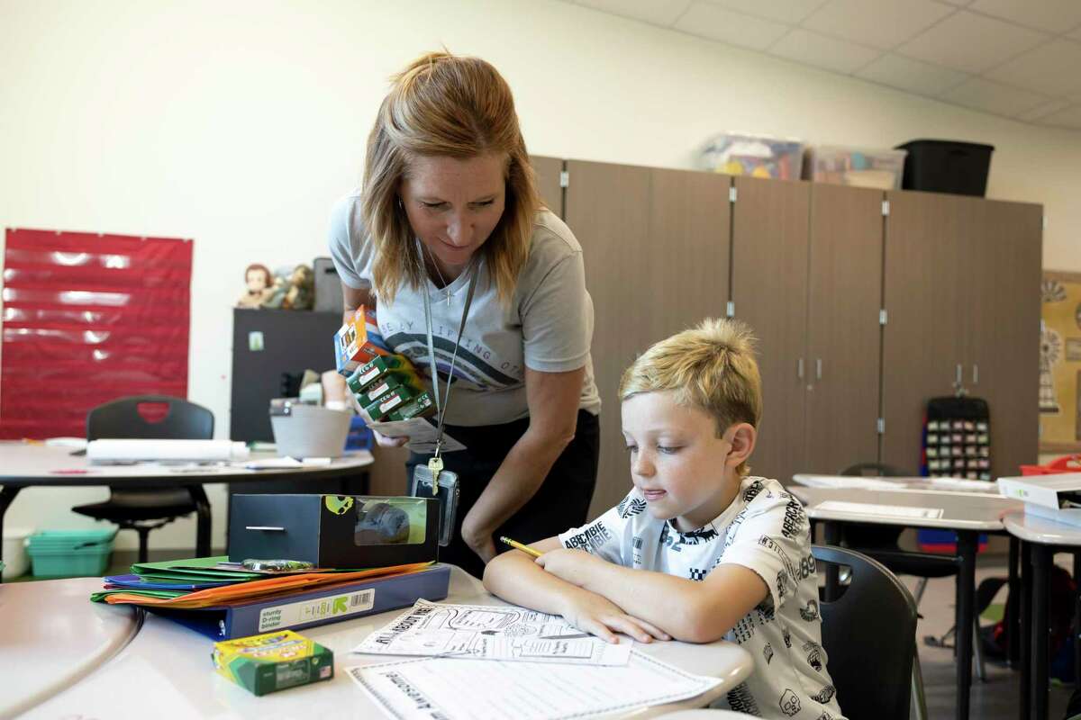 Nichole Slott, third grade teacher, left, assists Lukas Grimm with an assignment during the first day of school at Eddie Ruth Lagway Elementary, Wednesday, Aug. 11, 2021, in Conroe. The 101,930 square foot two-story building will house 850 kindergarten through fifth grade students.