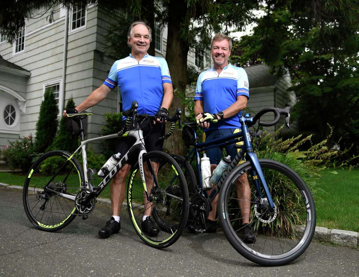 Alec Fraser, left, and Jamie Meehan pose with their bikes outside of Fraser's home in Old Greenwich, Conn. Wednesday, Aug. 4, 2021. Fraser lost his son, Julian, to cancer in 2017, and will be riding his bike across the country with Meehan later this month to raise money for cancer research.