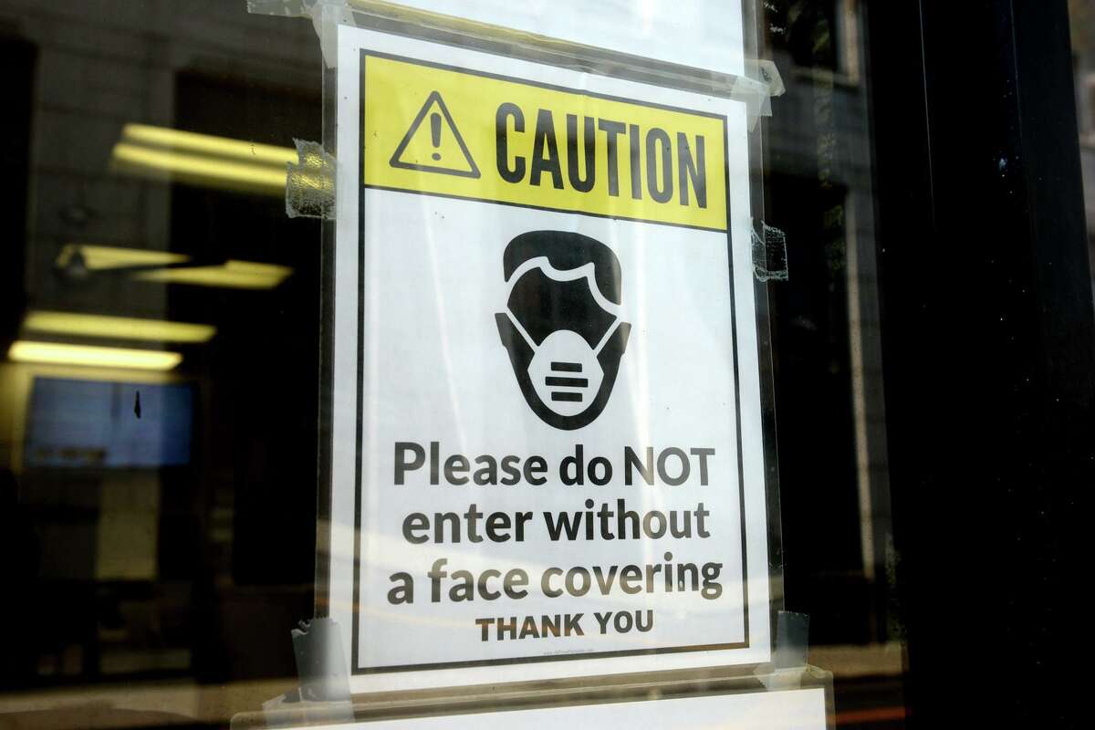 A sign requiring masks or face covering hangs on the front door of the Morton Government Center, in Bridgeport, Conn. Aug. 11, 2021.