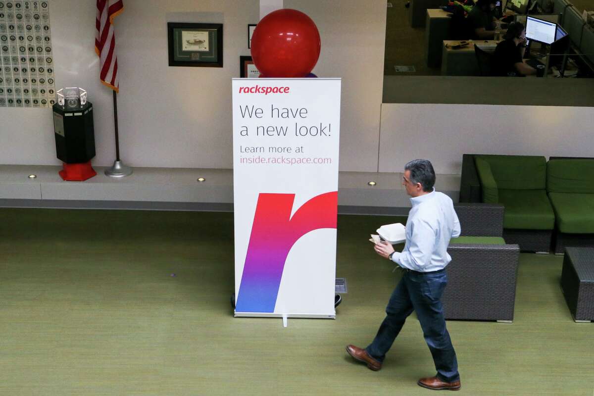 A Rackspace Technology Inc. employee walks past the company’s logo.