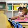 Calise Evans sits behind a plastic enclosure at her desk at Summit Elementary School in Summit, Miss., on Thursday, Aug. 5, 2021, during the first day of the 2021-22 school year for students in the McComb School District. The school district is requiring face masks on buses and campuses this school year. (Matt Williamson /The Enterprise-Journal via AP)