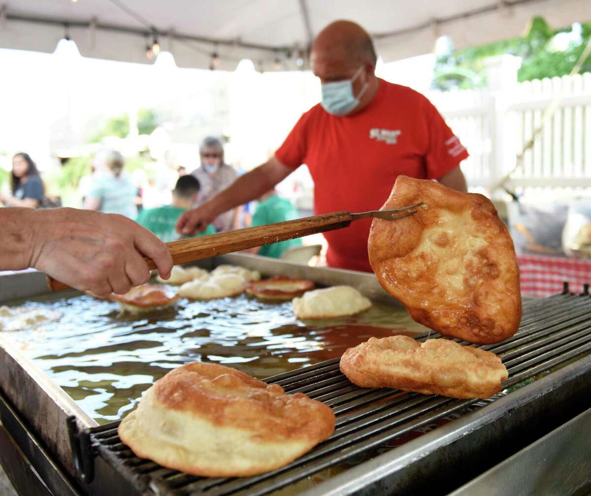 A deep fried pizza fritta is ready to be topped with cheese or powdered sugar at the St. Roch Feast at St. Roch Church and Hamilton Avenue School in the Chickahominy section of Greenwich, Conn. Wednesday, Aug. 11, 2021. The renowned event features live musical performances, carnival games and rides, a beer and wine garden, raffle, and delicious Italian food including sausage and pepper sandwiches and deep fried pizza fritta. St. Roch Feast runs from Wednesday through Saturday and culminates with Mass on Sunday.