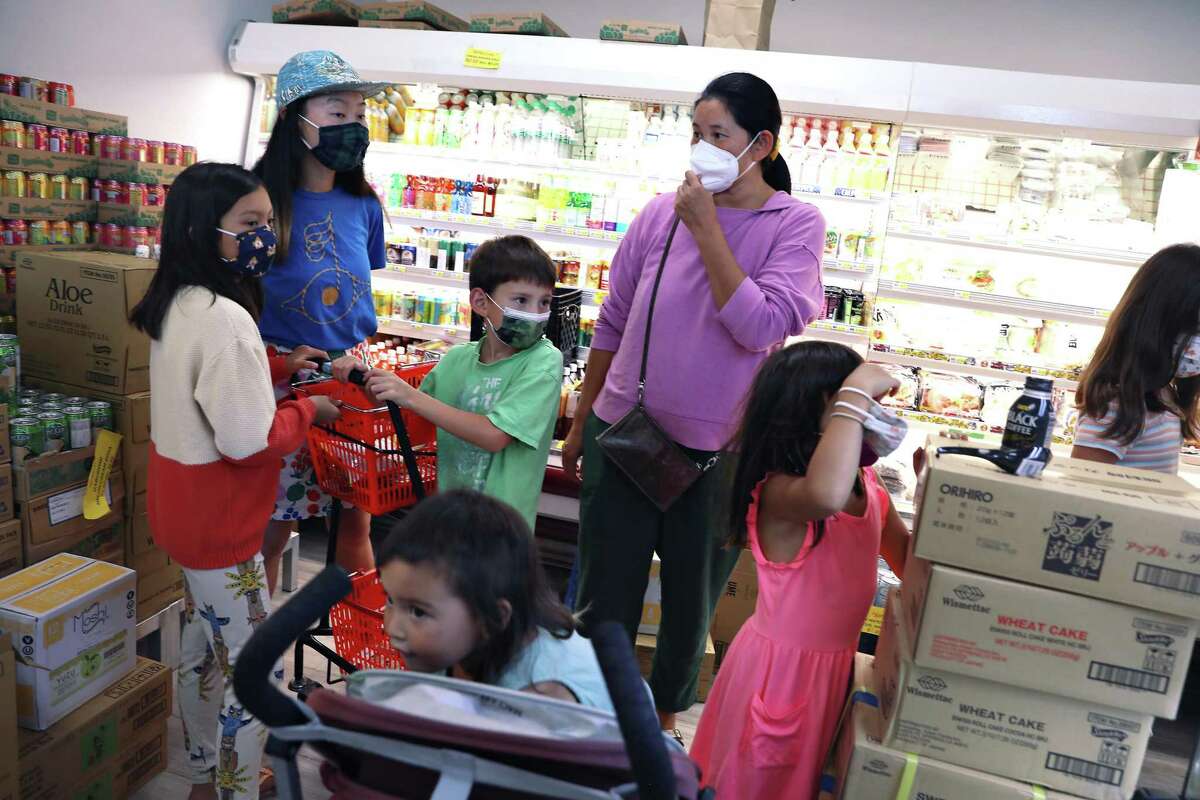 Keiko McClure (rear left) and Asel Ibragimova (rear right) shop with their children at Suruki Supermarket in San Mateo.