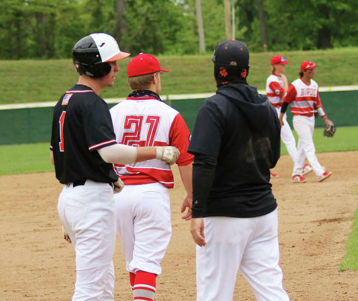 Edwardsville coach Tim Funkhouser gets a fist bump from his son and Tigers shortstop Evan Funkhouser at third base during a game last season at Alton High in Alton.