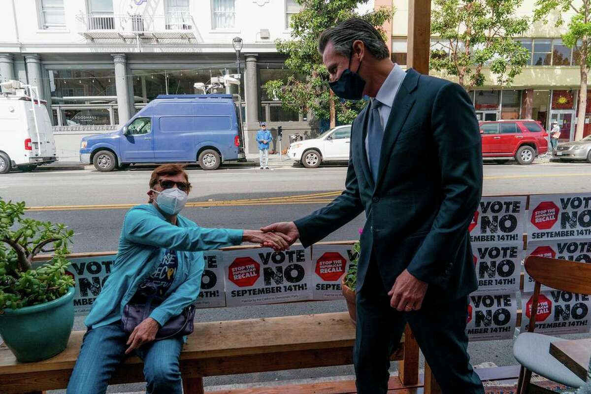 A woman shakes hands with Gov. Gavin Newsom in S.F. Newsom and his supporters are racing the clock to wake up fellow Democrats.