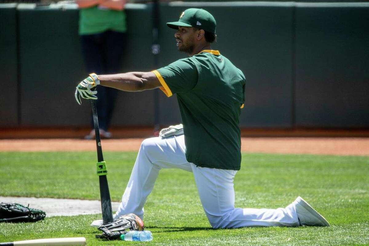 Oakland A's left fielder Khris Davis stretches during an Oakland A's training camp workout at O.Co Coliseum in Oakland, Calif. Tuesday, July 7, 2020. Due to COVID-19, the 2020 MLB season has been postponed with players just beginning to return for warmups and practices while wearing masks and keeping social distance.