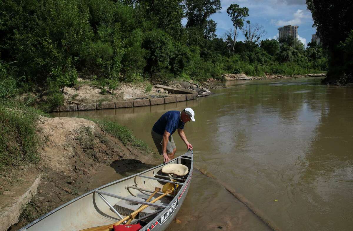 Tom Helm loads a canoe into Buffalo Bayou on Sunday, Aug. 8, 2021, in Houston.
