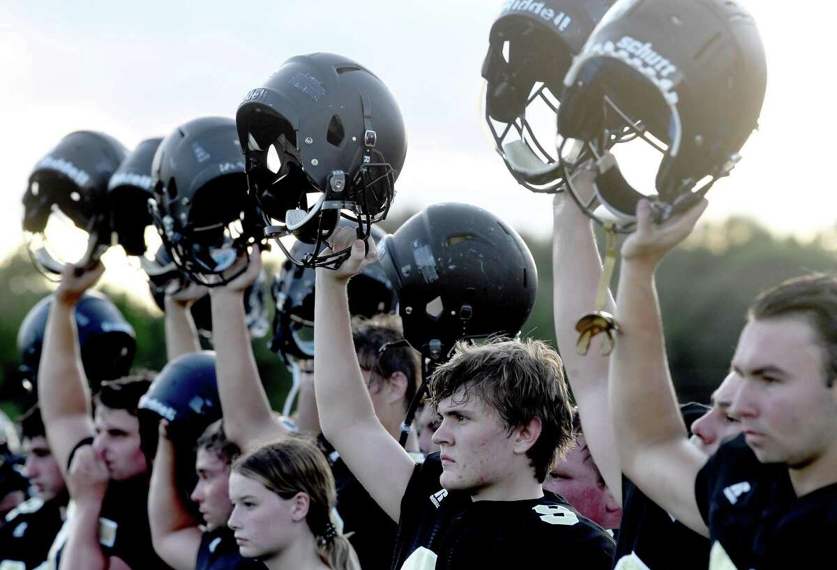 Vidor players raise their helmets for the opening kick-off as they face Buna at home in their season opening scrimmage. Photo made Friday, August 13, 2021 Kim Brent/The Enterprise
