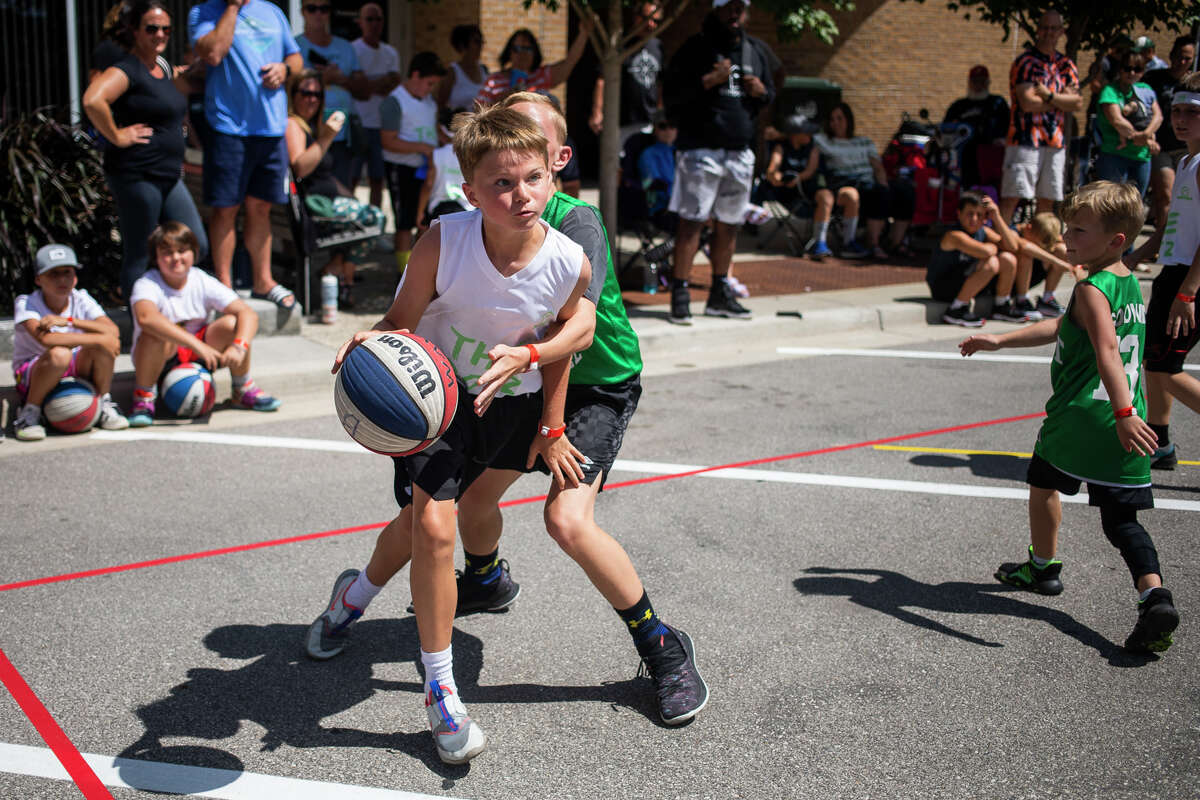 Tanner Murphy, 10, dribbles towards the basket as hundreds of athletes compete in the Gus Macker 3 on 3 basketball tournament Saturday, Aug. 14, 2021 in downtown Midland. (Katy Kildee/kkildee@mdn.net)