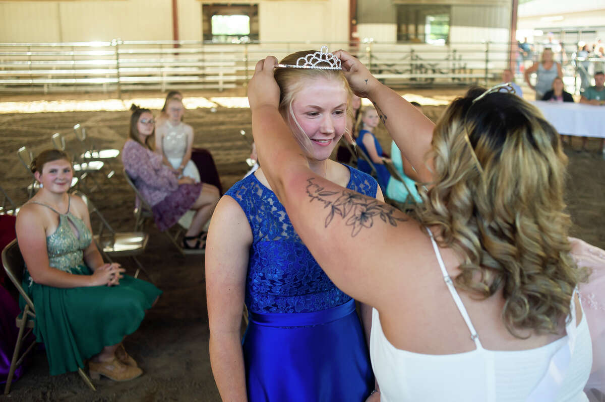 Audrey Martin, 16, left, is given her tiara and sash by Dani Skutt, the 2019 Midland County Fair Queen, right, after Martin was named Queen in the 2021 Midland County Fair Royalty Contest Saturday, Aug. 14, 2021 at the Midland County Fairgrounds. (Katy Kildee/kkildee@mdn.net)