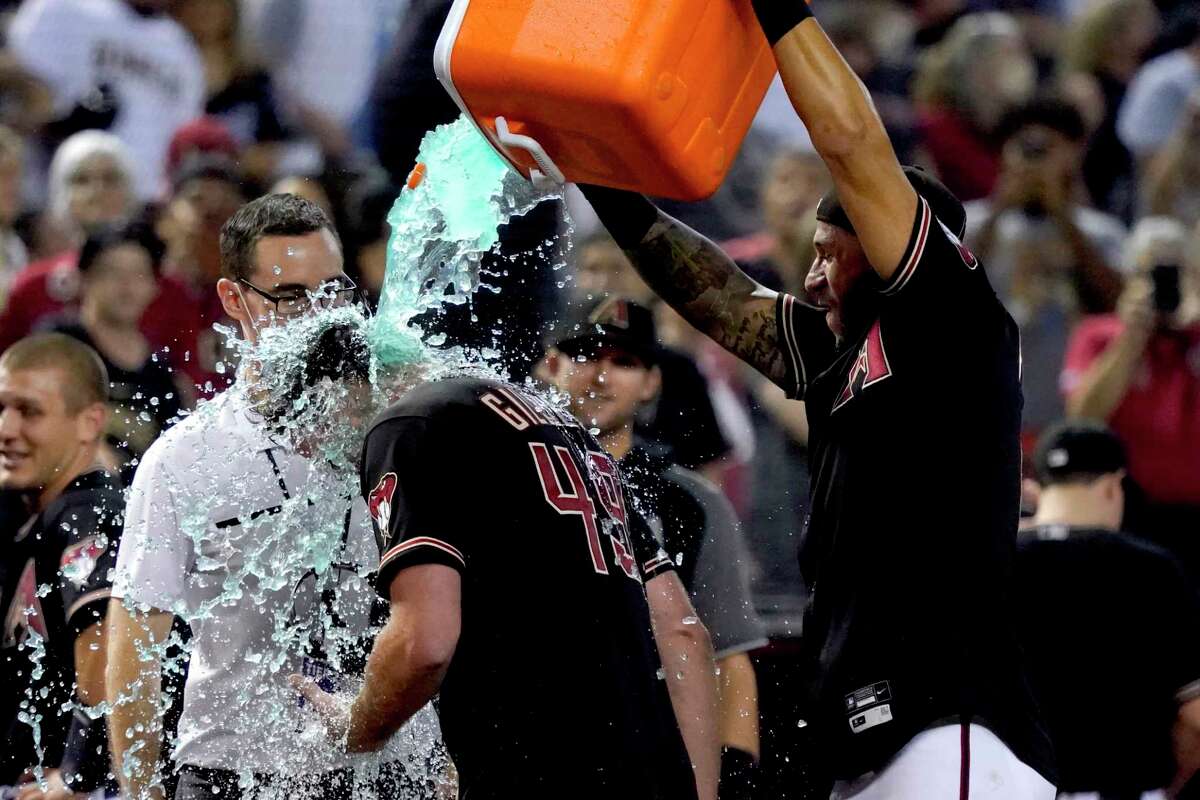 Arizona Diamondbacks left fielder David Peralta, right, soaks starting pitcher Tyler Gilbert after his no-hitter against the San Diego Padres in a baseball game Saturday, Aug. 14, 2021, in Phoenix. It was Gilbert's first career start. The Diamondbacks won 7-0.