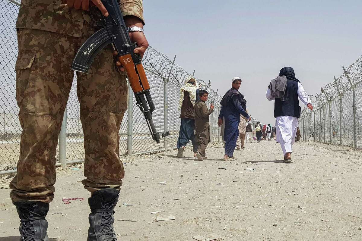 A Pakistani soldier stands guard at the border as stranded Afghans return to Afghanistan after the Taliban took control of the border town of Chaman. Afghan residents of the Bay Area are fearful for their relatives and friends still living in Afghanistan.