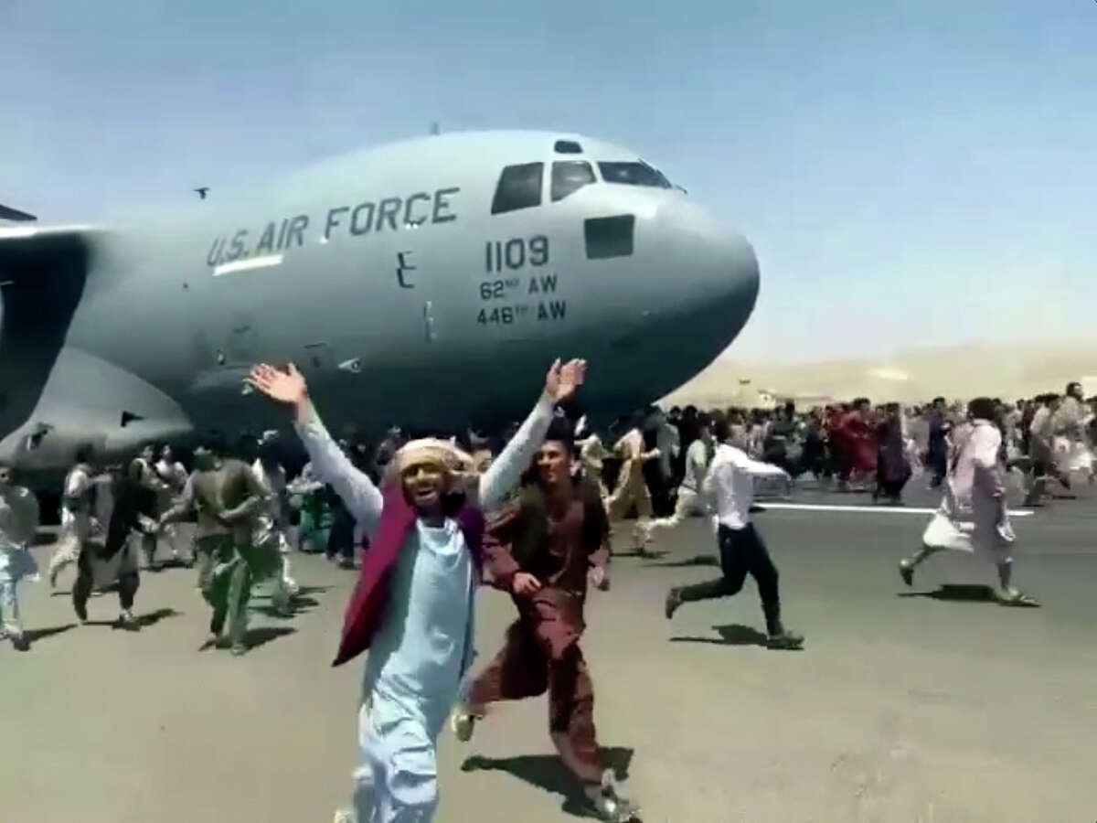 Hundreds of people run alongside a U.S. Air Force C-17 transport plane as it moves down a runway of the international airport, in Kabul, Afghanistan, Monday, Aug.16. 2021. Thousands of Afghans have rushed onto the tarmac of Kabul's international airport, some so desperate to escape the Taliban capture of their country that they held onto an American military jet as it took off and plunged to death. (Verified UGC via AP)