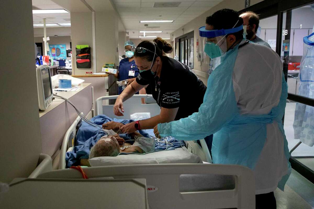Medical staff help a COVID patient in the hallway at the emergency room at the Texas Vista Medical Center.
