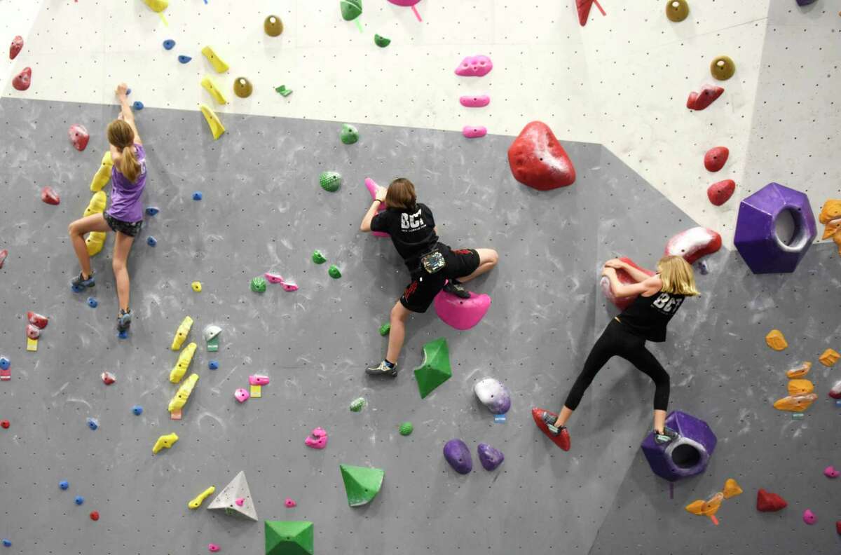 Lillian Back, left, 11, Malia Hernandez, center, 15, and Eliza Harper, 9, scale the rock wall at Beta Climbing + Fitness in Stamford, Conn. Monday, Aug. 16, 2021. Local climbing gyms have seen a recent uptick in participation following the sport's debut at the Olympics.