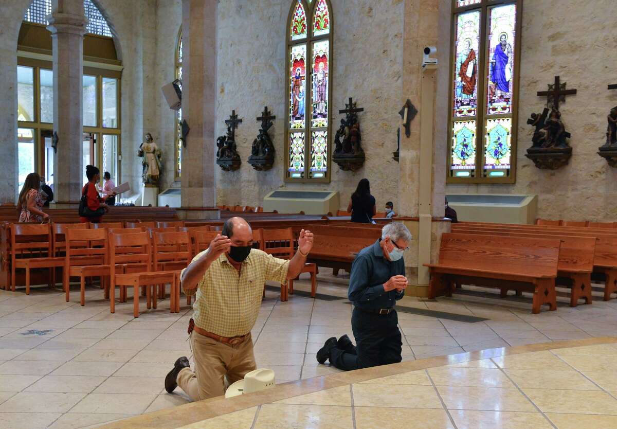 David Vasquez and Rolando Reyes wear masks and pray following Sunday Mass at San Fernando Cathedral.
