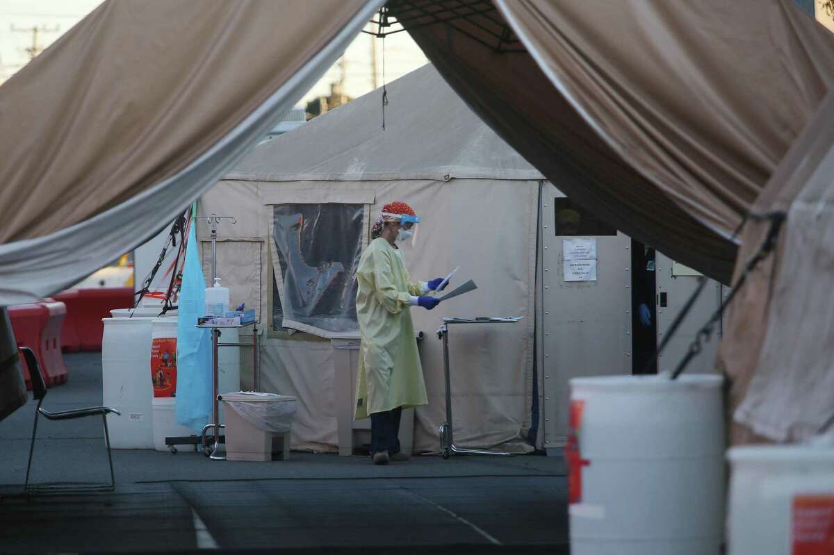 A worker at a COVID-19 test site on Armstrong at Keith Street carries paperwork and a test kit on Friday, November 27, 2020 in San Francisco, Calif.