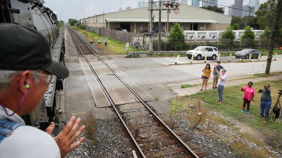 People wave at Ed Dickens and Union Pacific’s steam locomotive Big Boy No. 4014 as it rolls towards downtown Monday, Aug. 16, 2021, in Houston. People lined the track from Hearne to Houston as the train made the trip Monday.