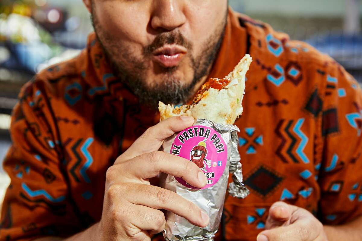 Ozi Magaña, who runs an Instagram reviewing burritos, bites into a burrito at Al Pastor Papi's food truck.