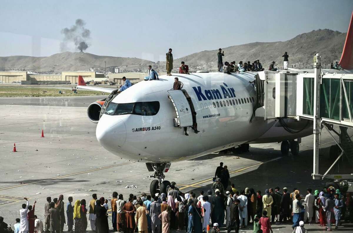 People climb atop a plane as they wait at the Kabul airport, hoping to flee the Taliban. The U.S. must do all it can to get Afghans out of the country.